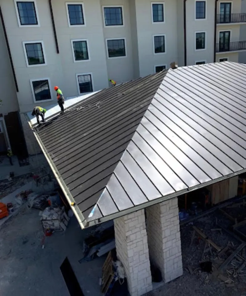 Crew installing standing seam metal roof panels on a commercial project in Bourne